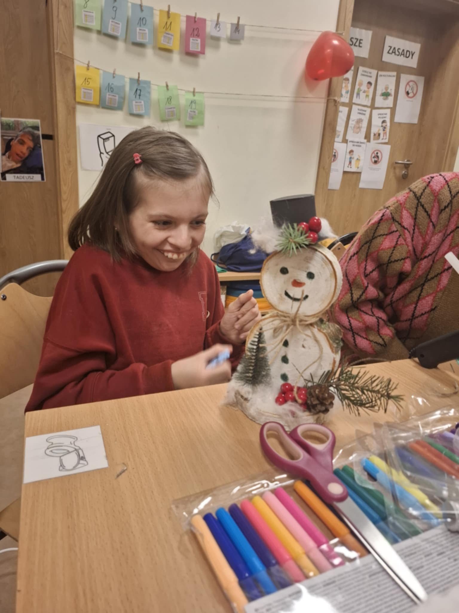 Dziewczynka pokazuje bałwanka, którego stworzyła razem z mamą podczas warsztatów.