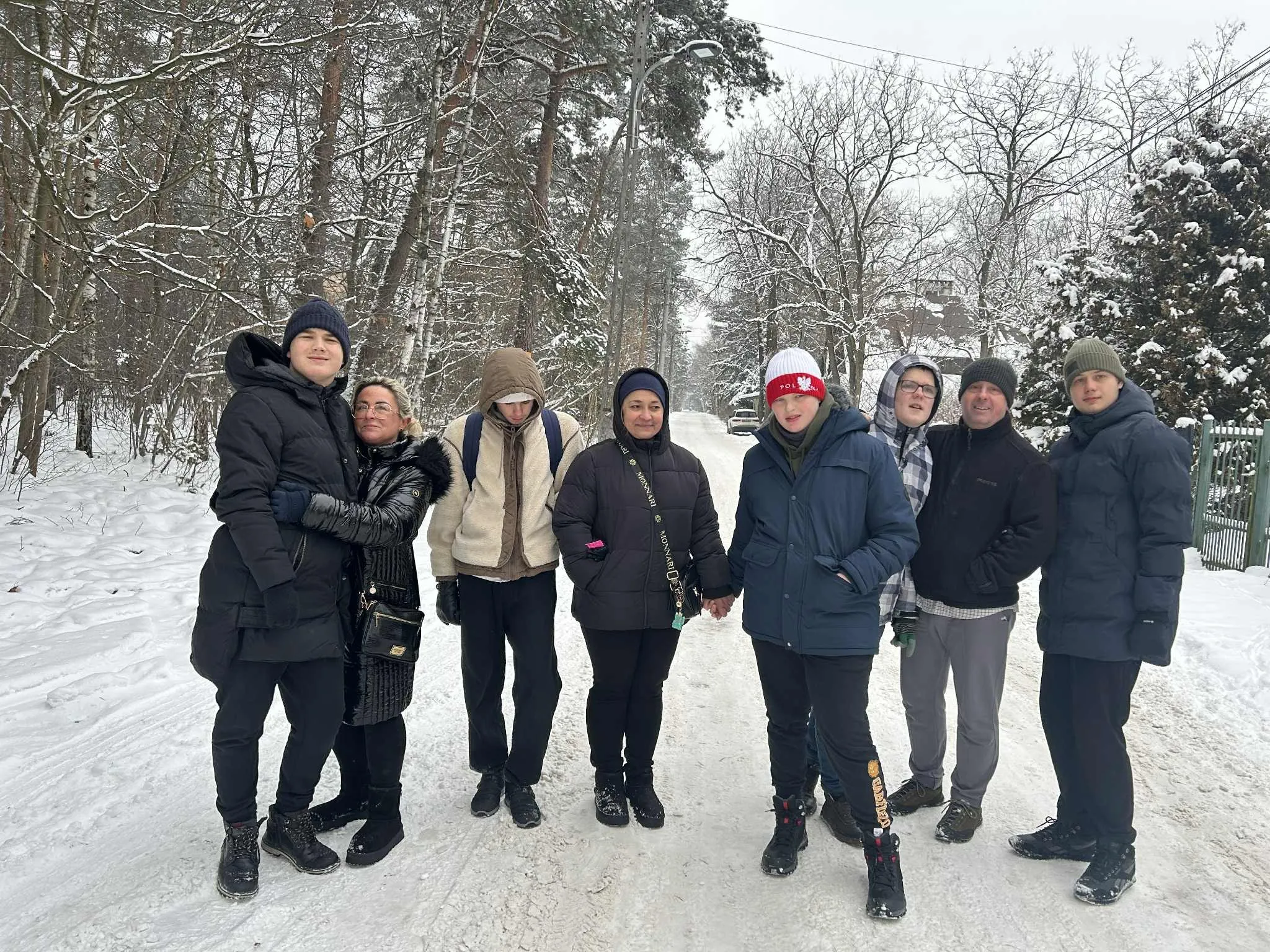 Młodzież na spacerze zimą w lesie. 
