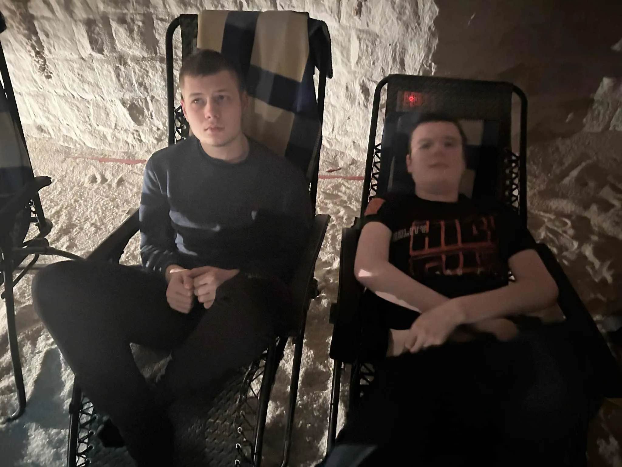 2 chłopców siedzi na leżakach w grocie solnej.