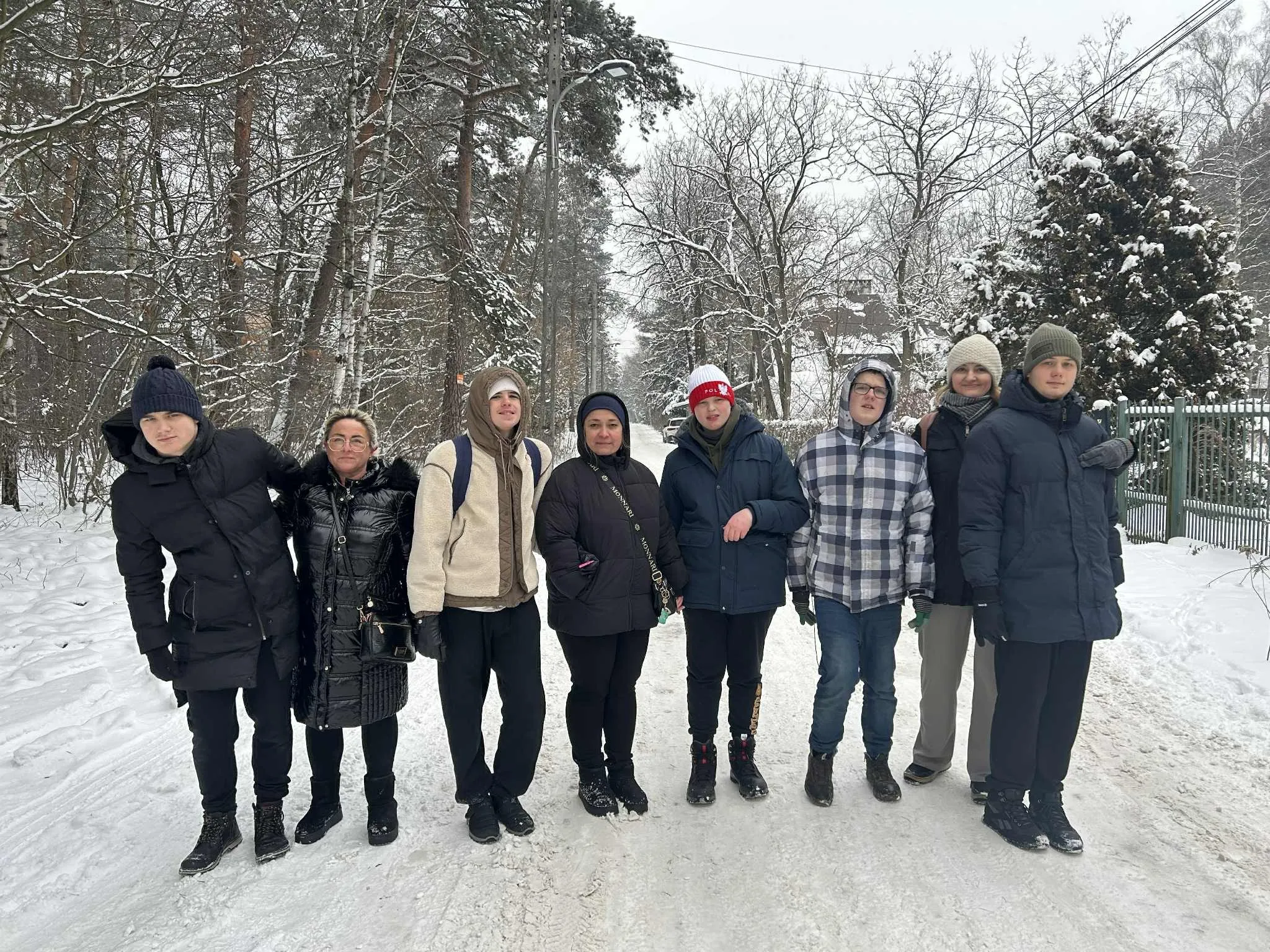 Młodzież na spacerze zimą w lesie. 
