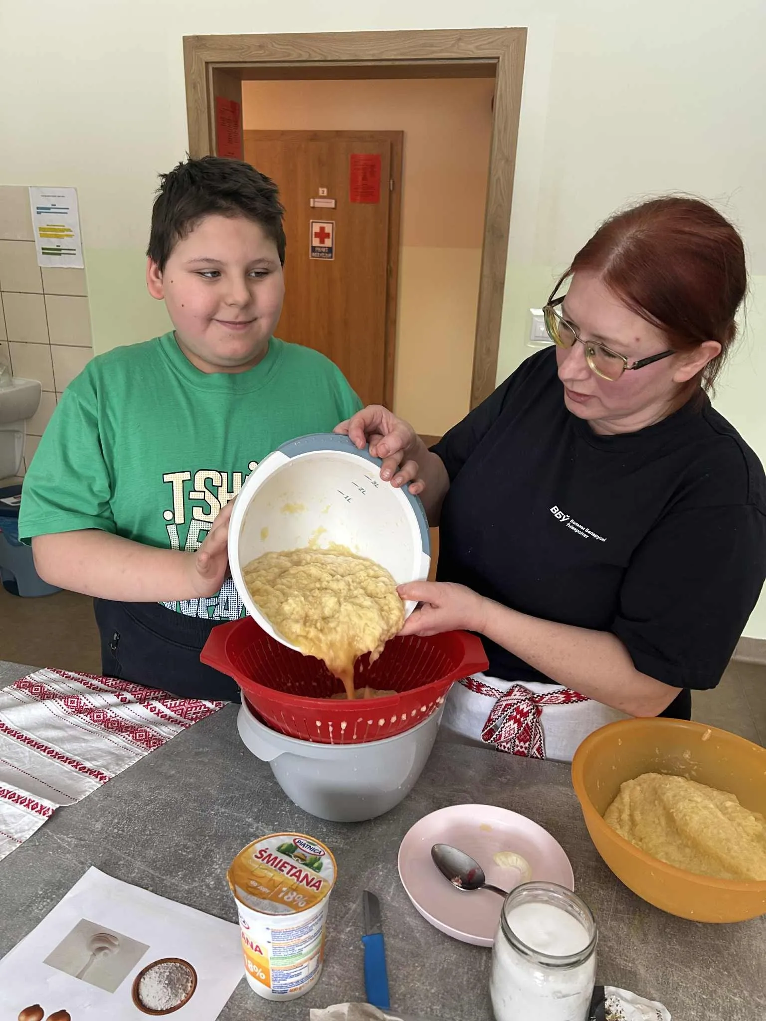 Chłopiec z panią wlewa starte ziemniaki do miski.